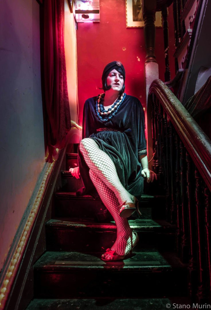 A cabaret artist sitting on stairs