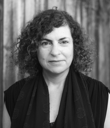 A close up of a white woman with short curly hair. She is smiling.